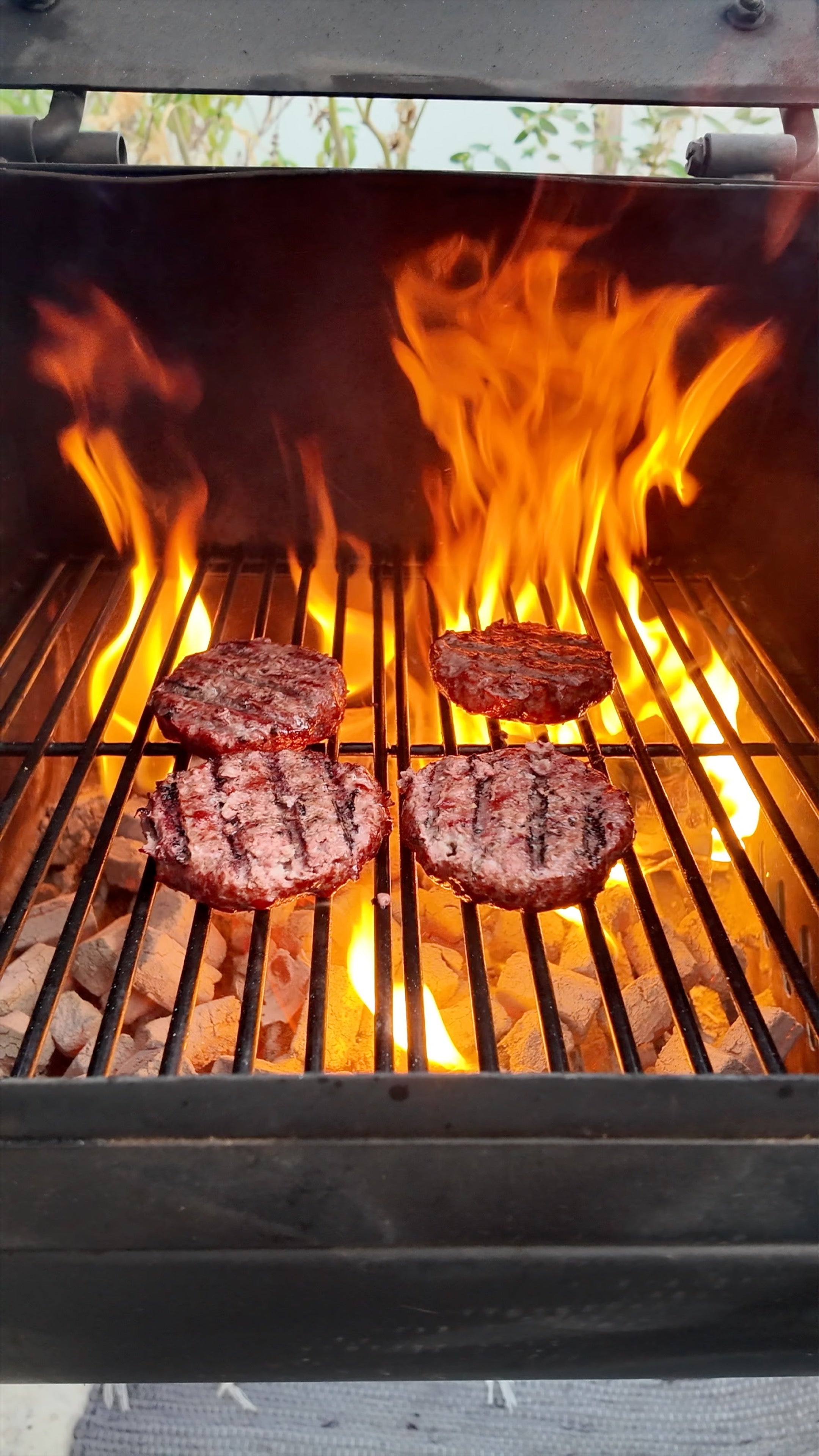 Hamburgers cooking on a grill with flames